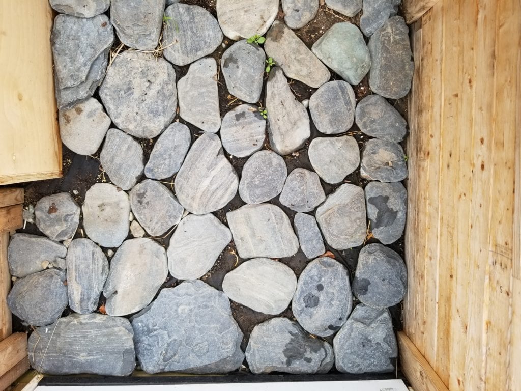 Use drak beach rocks to retain heat in your greenhouse